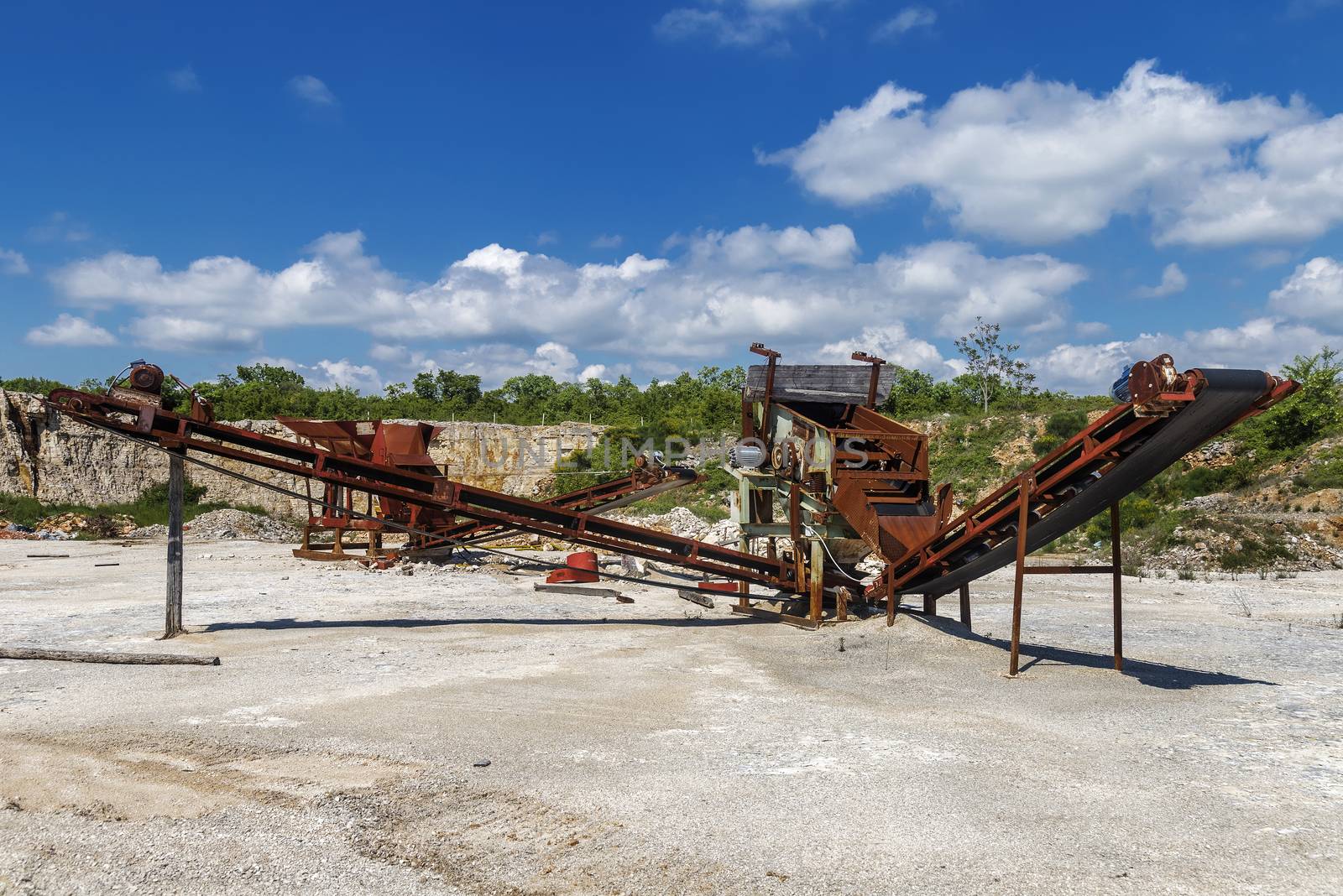Old rusty stone crushing machines in abandoned quarry