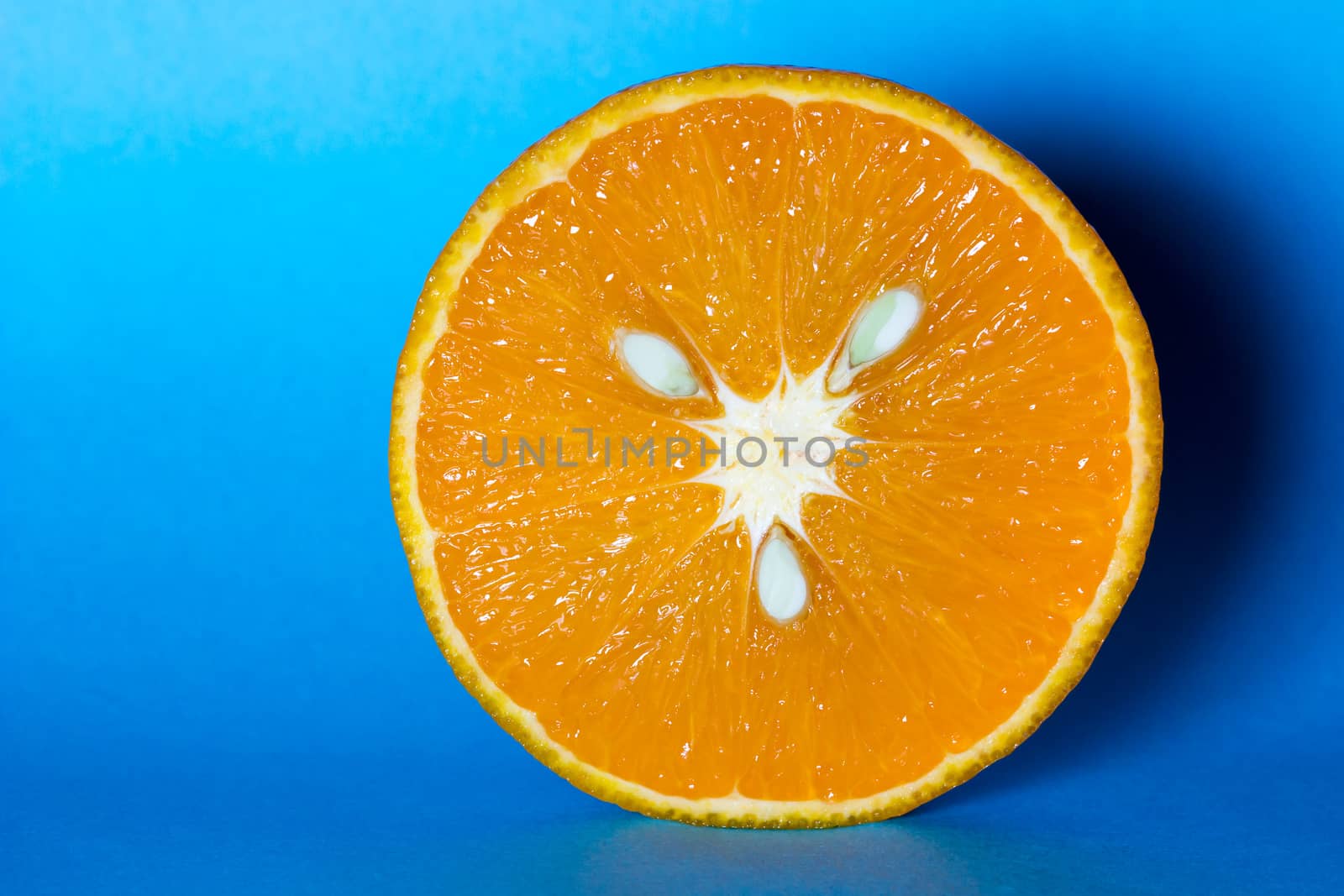 Fresh and juicy orange with seeds on light blue background.