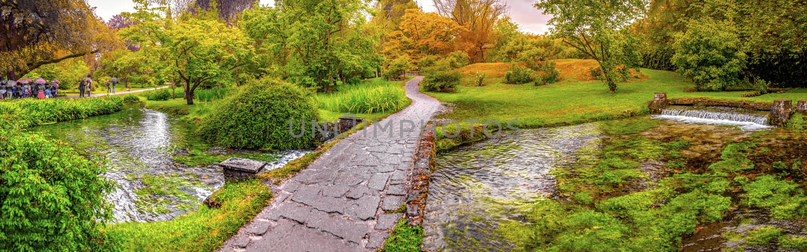 enchanted eden garden path bridge trail over pond in horizontal panoramic garden .