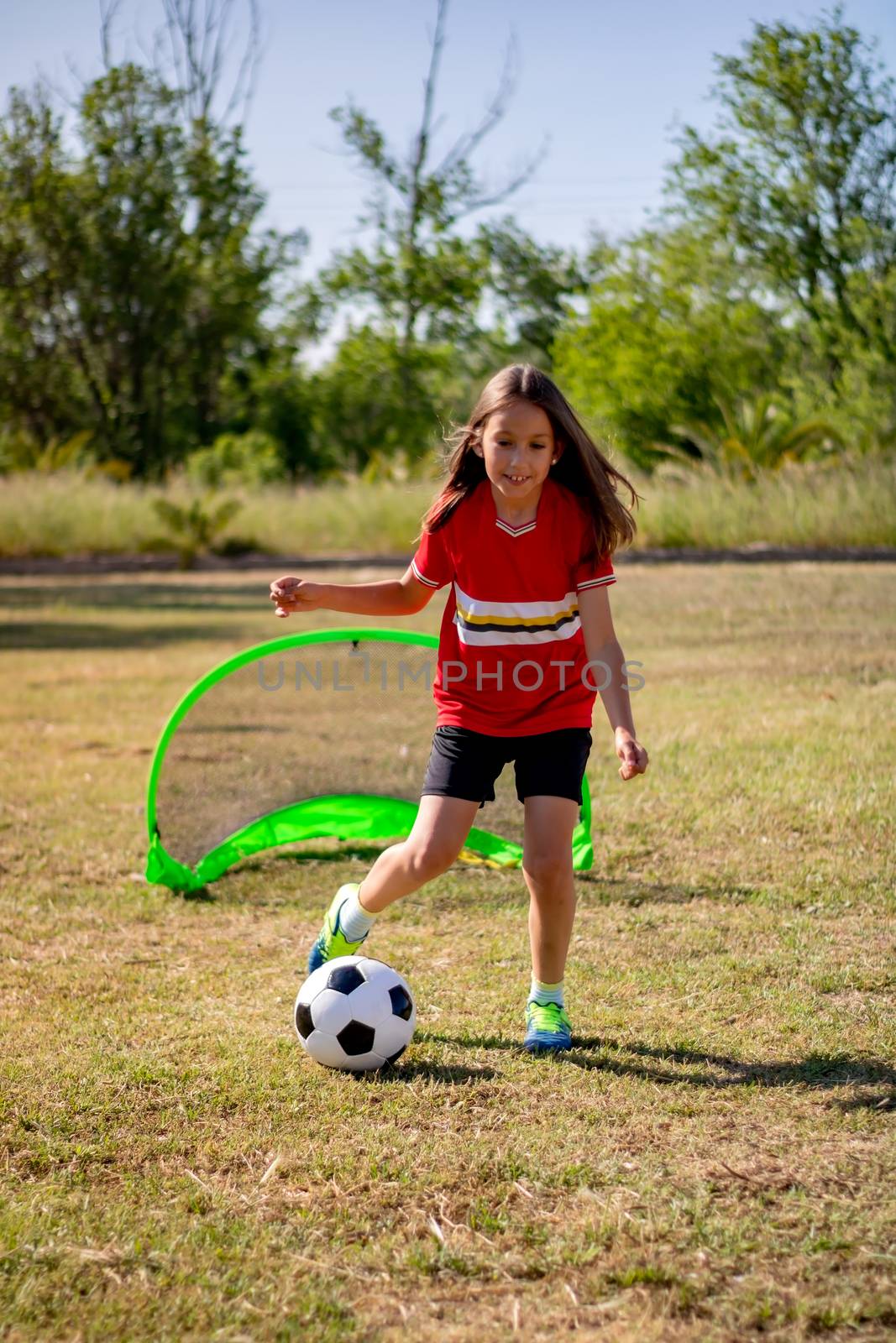 Little girl playing soccer on grassy esplanade
