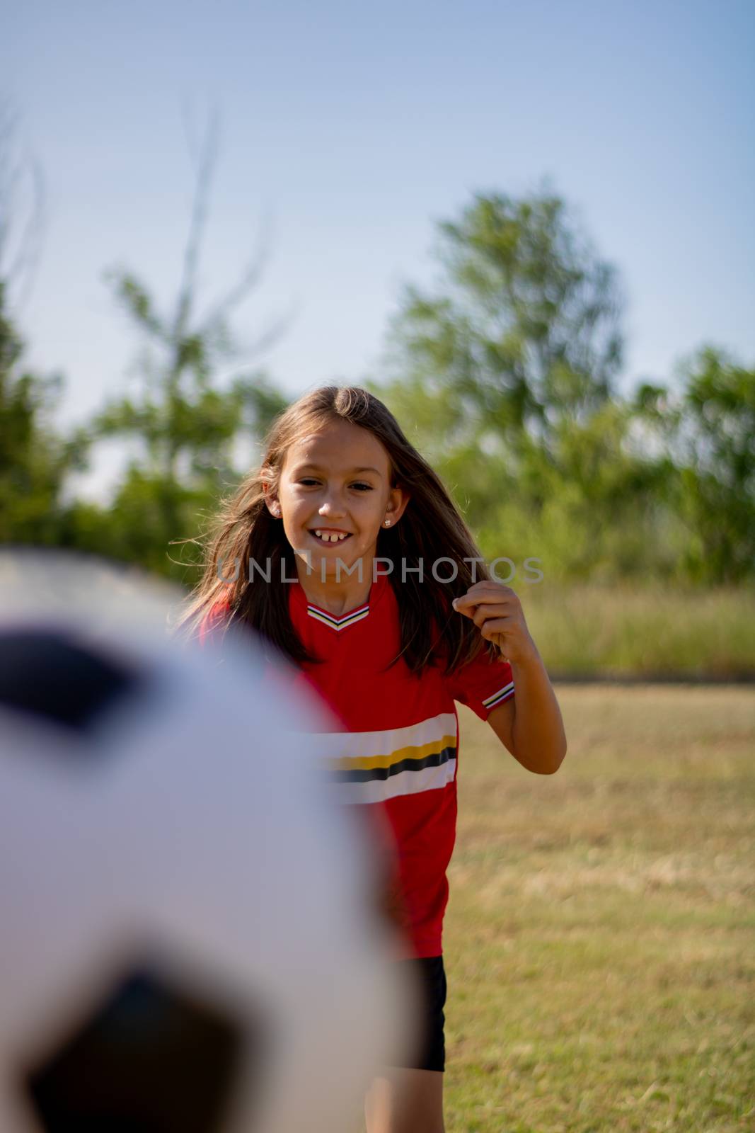 Little girl playing soccer on grassy esplanade