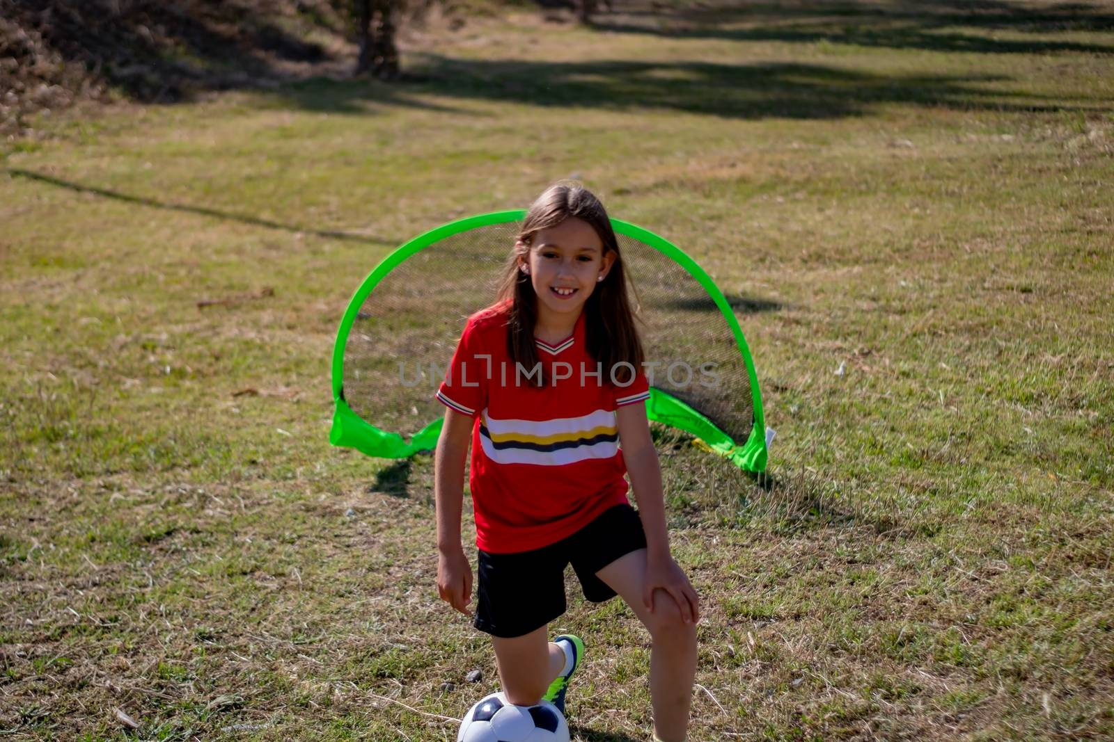 Little girl playing soccer on grassy esplanade