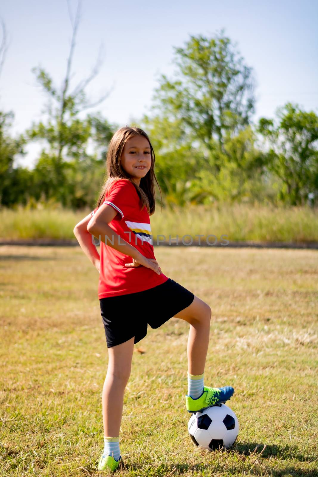 Little girl playing soccer on grassy esplanade