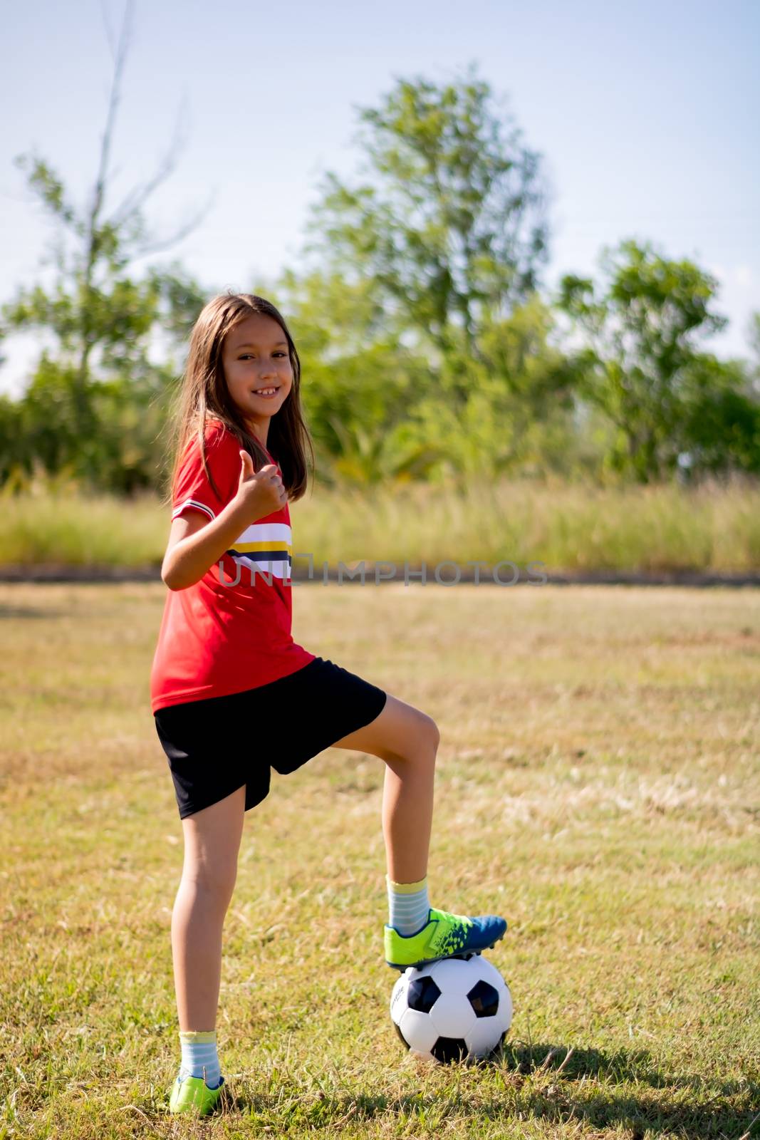 Little girl playing soccer on grassy esplanade