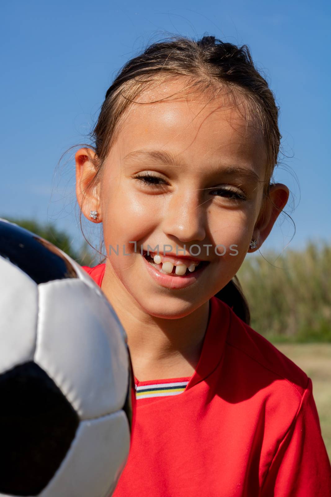 Little girl playing soccer on grassy esplanade