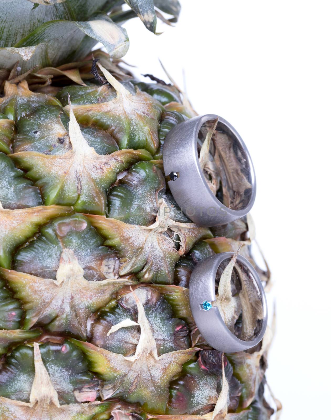 Wedding rings on a pineapple, isolated on a white background