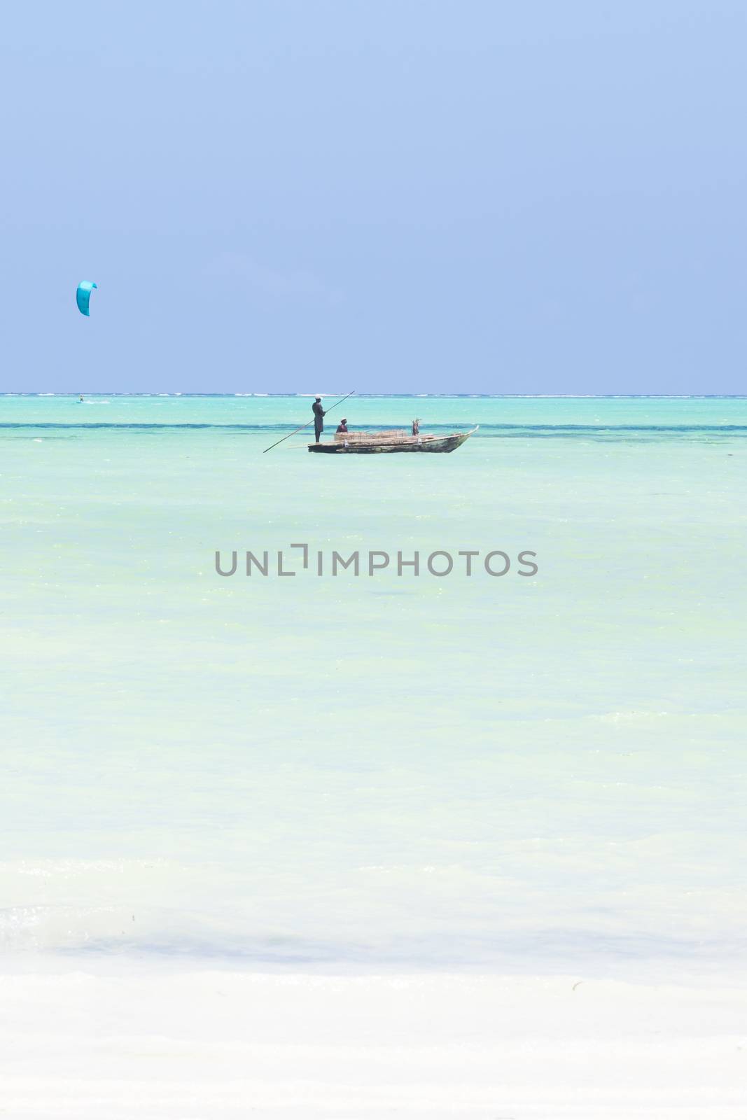 fishing boat and a kite surfer on picture perfect white sandy beach with turquoise blue sea, Paje, Zanzibar, Tanzania. by kasto