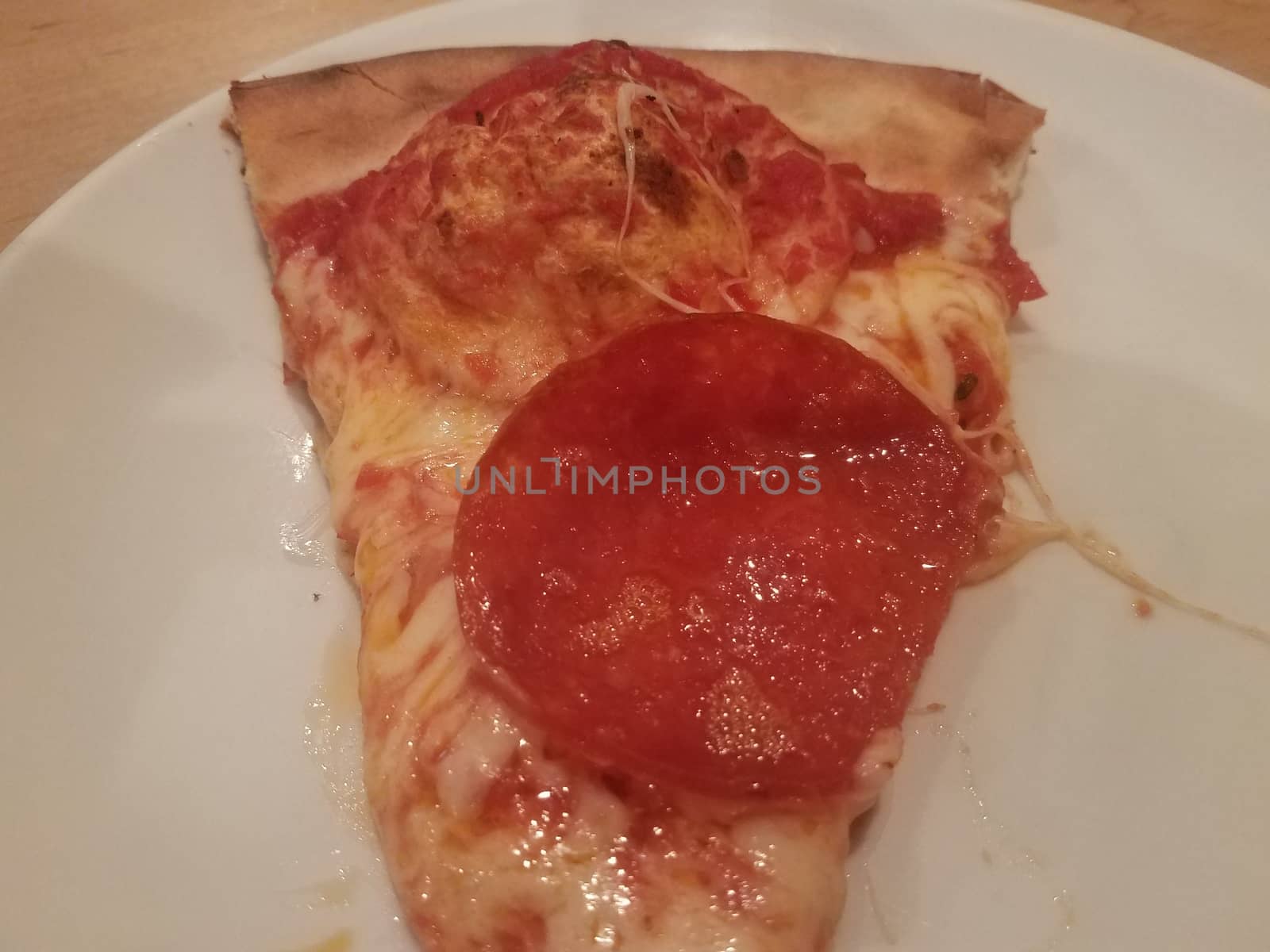 slice of pepperoni pizza with large pepperoni on white plate