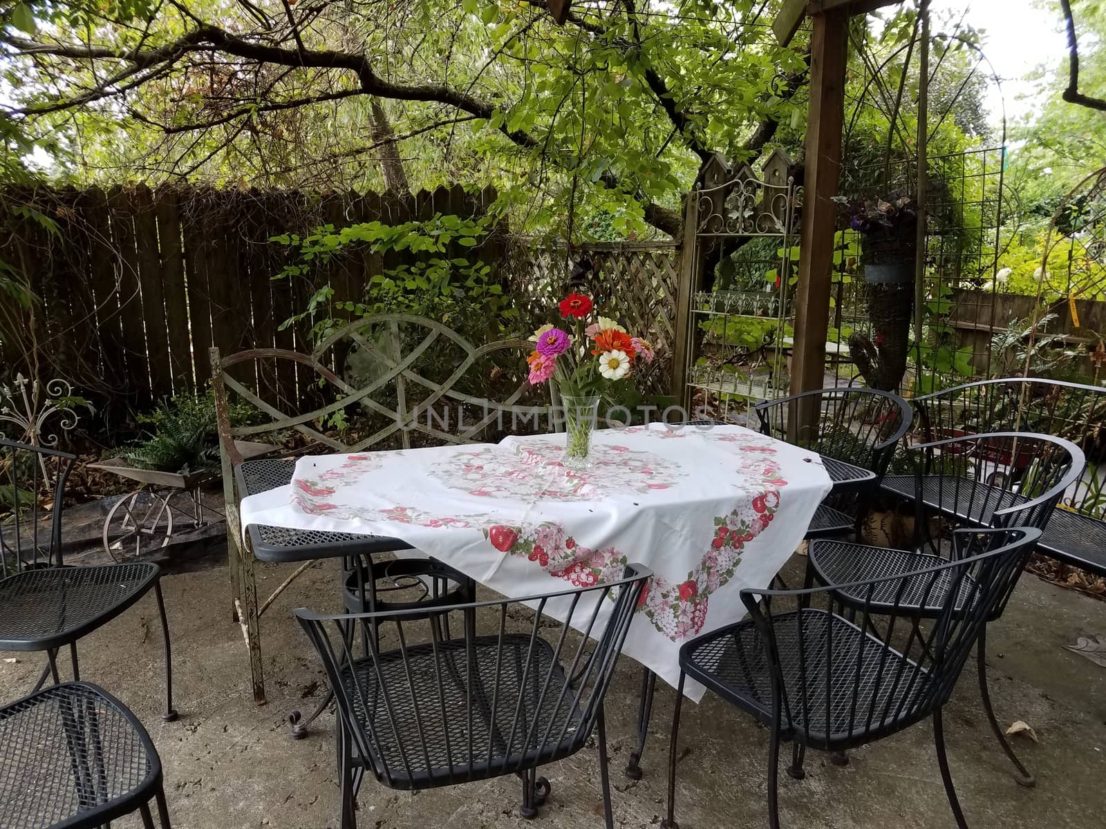 metal chairs and table with tablecloth and flowers in vase