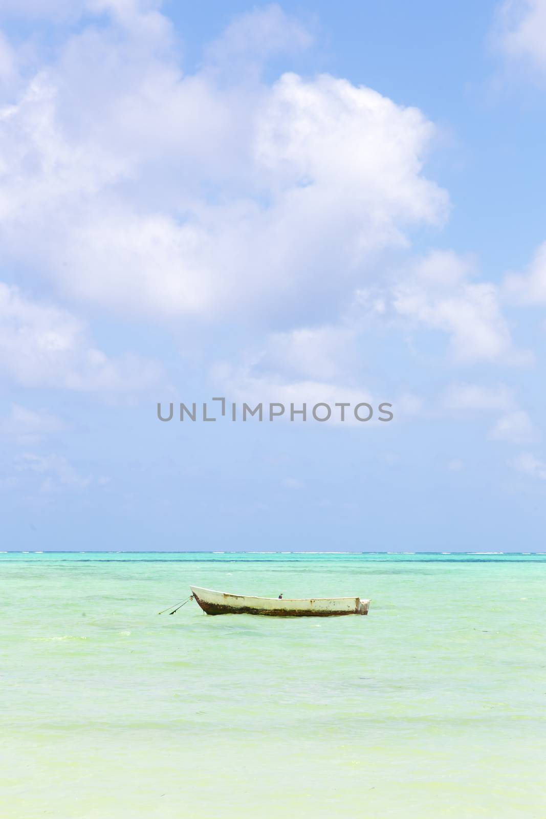 Solitary fishing boat on picture perfect white sandy beach with turquoise blue sea, Paje, Zanzibar, Tanzania. Copy space.