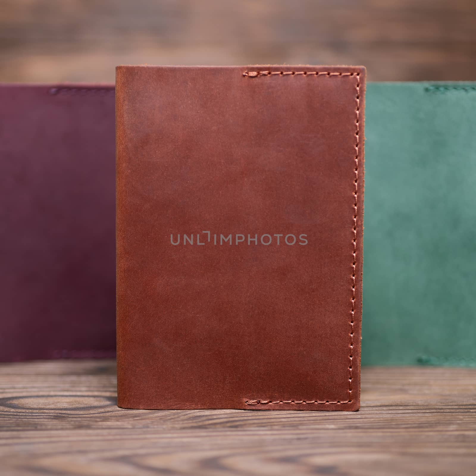 Ginger color handmade leather passport cover on blurred wooden background. Businessman`s accessory.