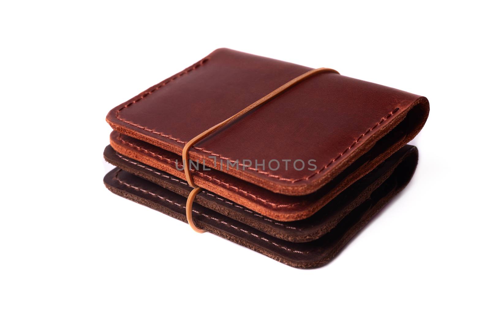 Handmade two red and brown leather cardholders with rubber band isolated on white background closeup. Stock photo of handmade luxury accessories.