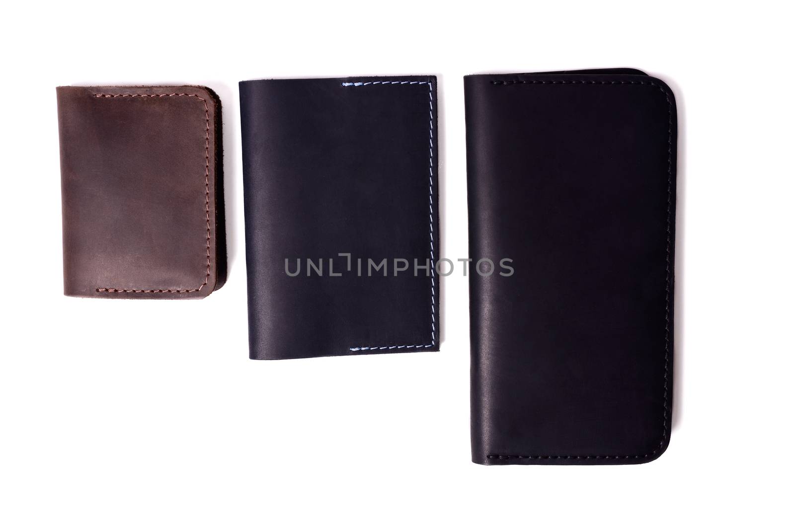 Handmade brown cardholder, black passport cover and purse isolated on white background closeup. Stock photo of isolated handmade luxury accessories.