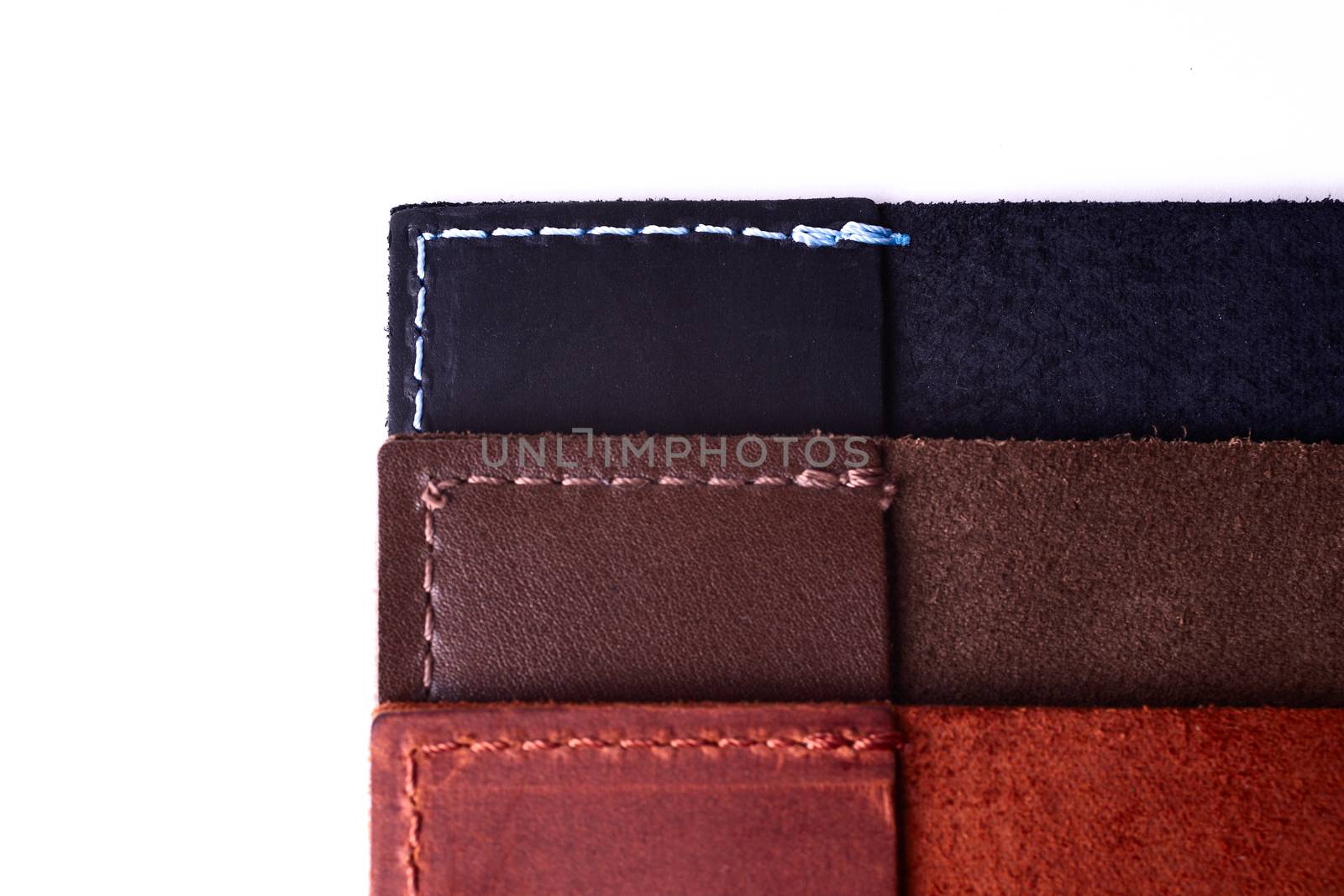 Three handmade leather passport covers stack isolated on white background. Closeup view. Covers are dark blue, red, brown and opened.