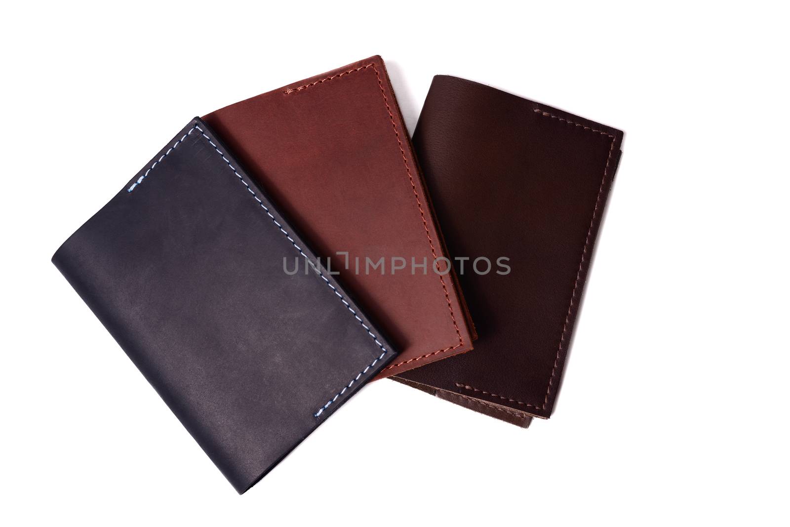 Three handmade leather passport covers isolated on white background. Closeup view. Covers are dark blue, red, brown and closed. by alexsdriver