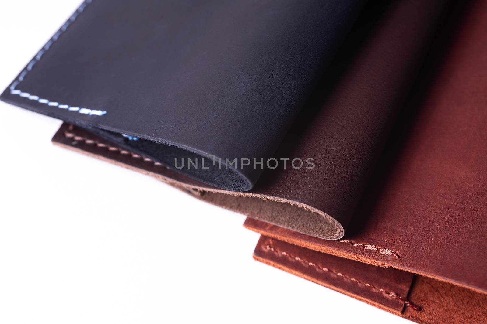 Three handmade leather passport covers isolated on white background. Covers are closed. Closeup view. Covers are dark blue, red and brown. by alexsdriver