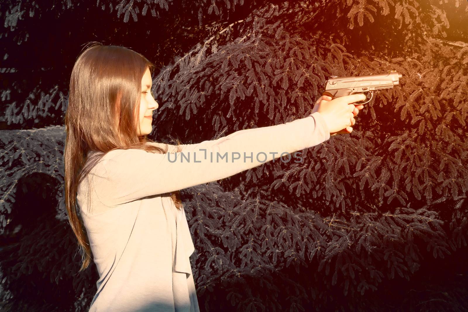 Pretty young Girl aiming from a pneumatic gun, outdoors.