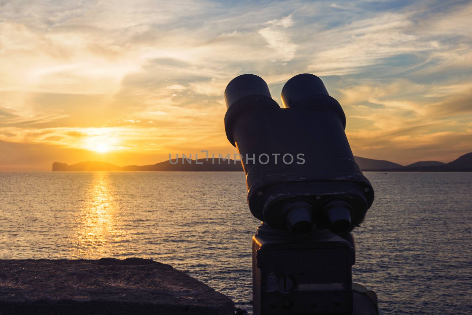 binoculars for tourists during the sunset in front of the giant that sleeps in the Gulf of Alghero, Sardinia, Italy