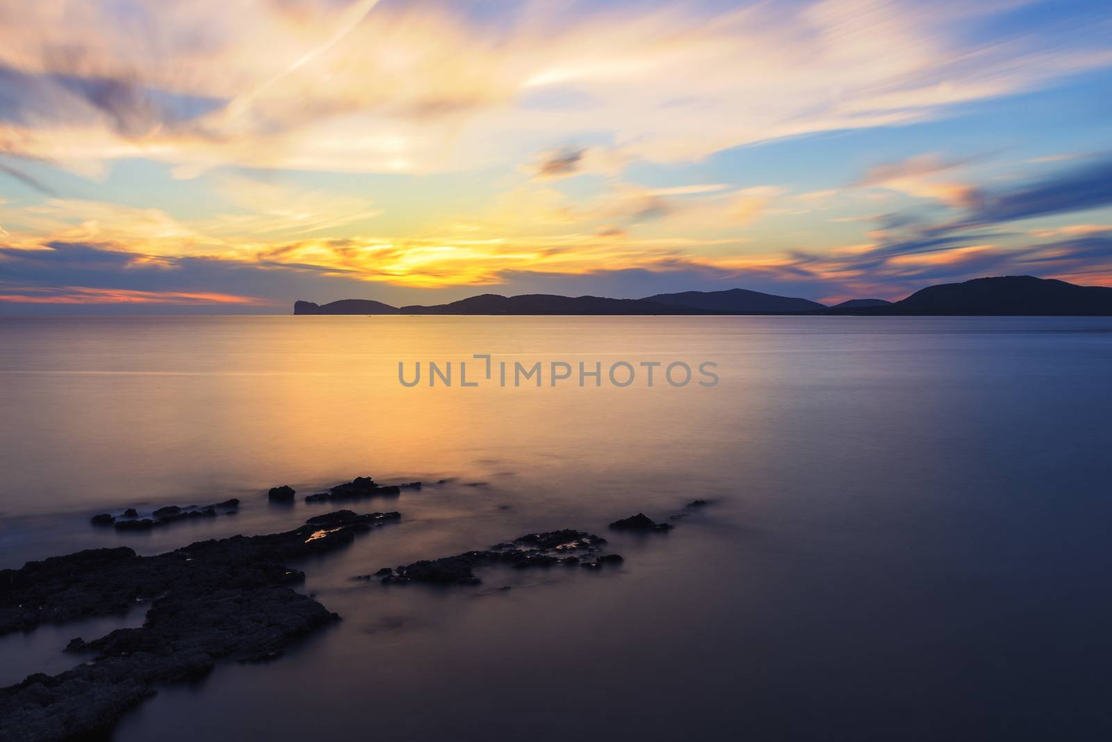 spectacular colorful sunset in the Gulf of Alghero, Sardinia, Italy. long exposure technique