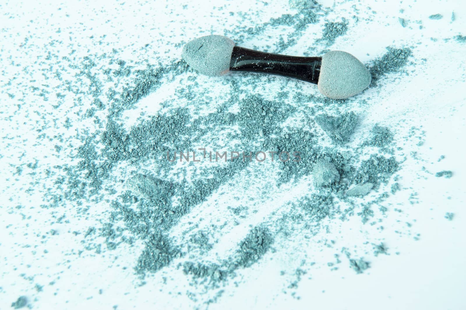 Scattered olive and green eyeshadow with applicator, isolated on white background, beauty and makeup concept.