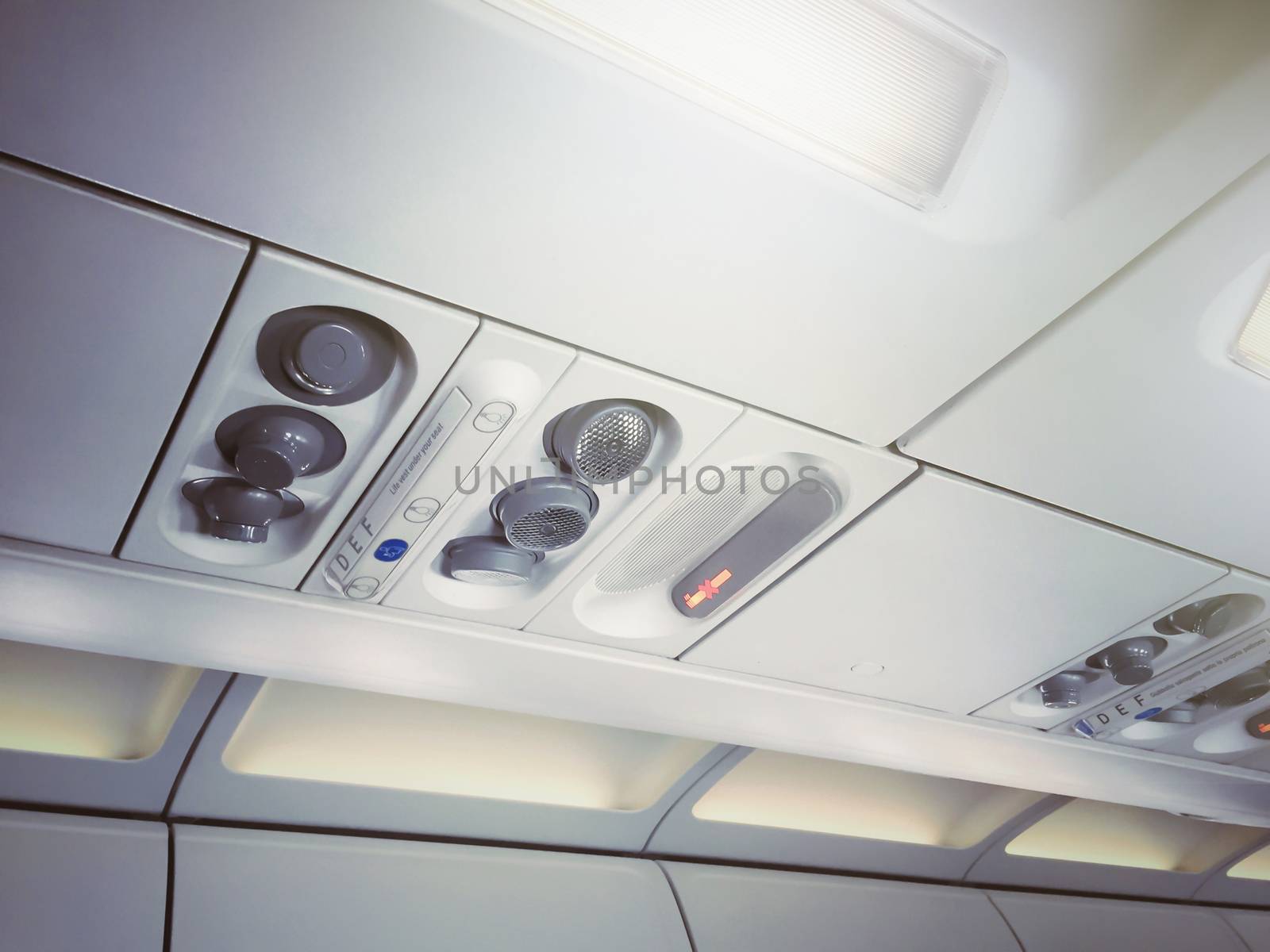 No smoking signs and controls for adjusting the air conditioning and personal lights inside a commercial aircraft. Concept of safety, transport and travel. Illuminated corridor of an airplane