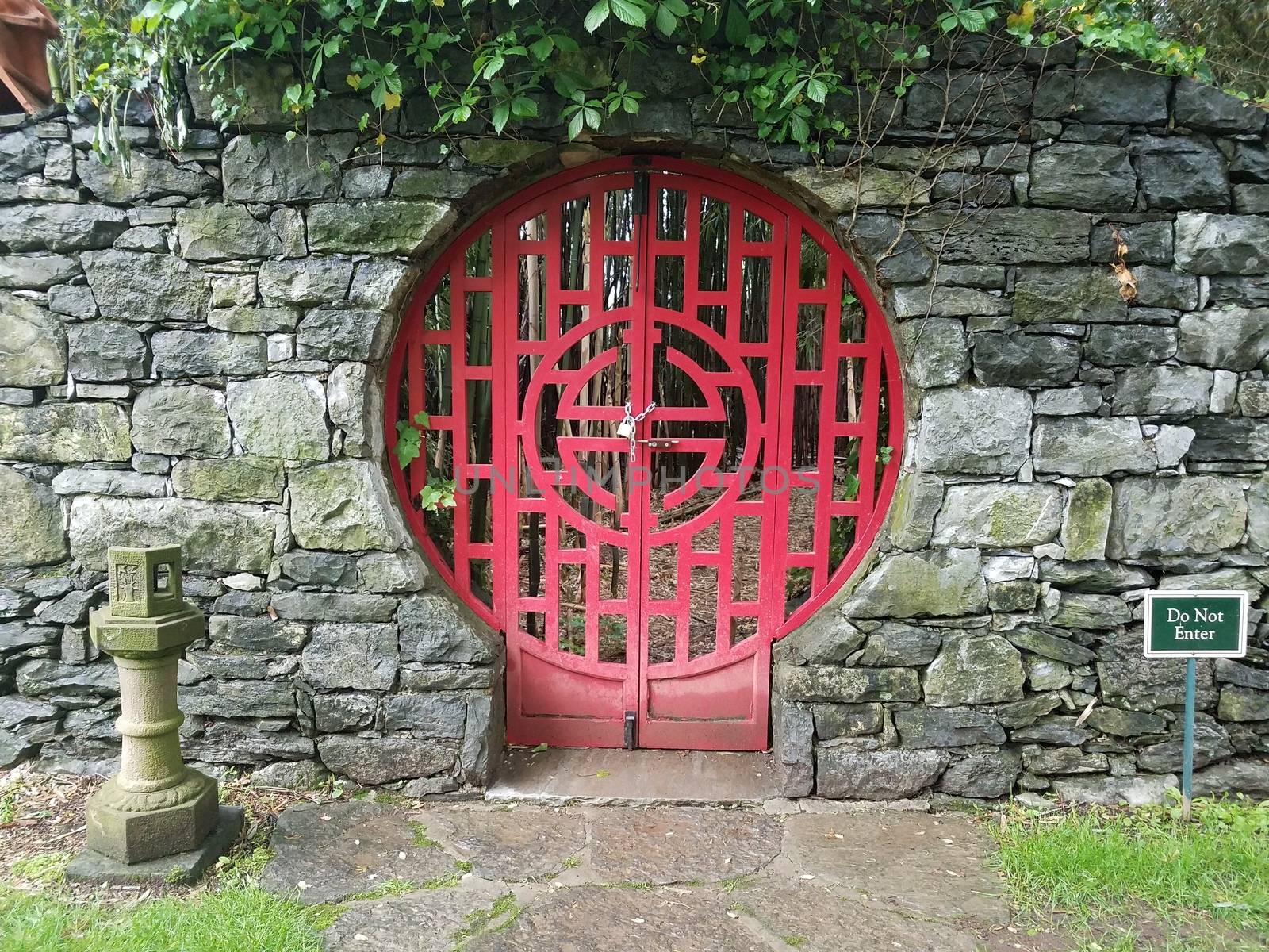 locked red door at Chinese garden with do not enter sign and stone wall