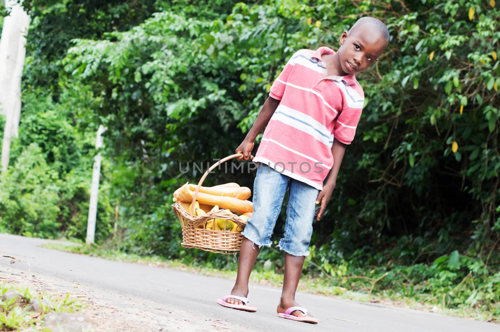 child holding a basket of food containing fruit and bread.