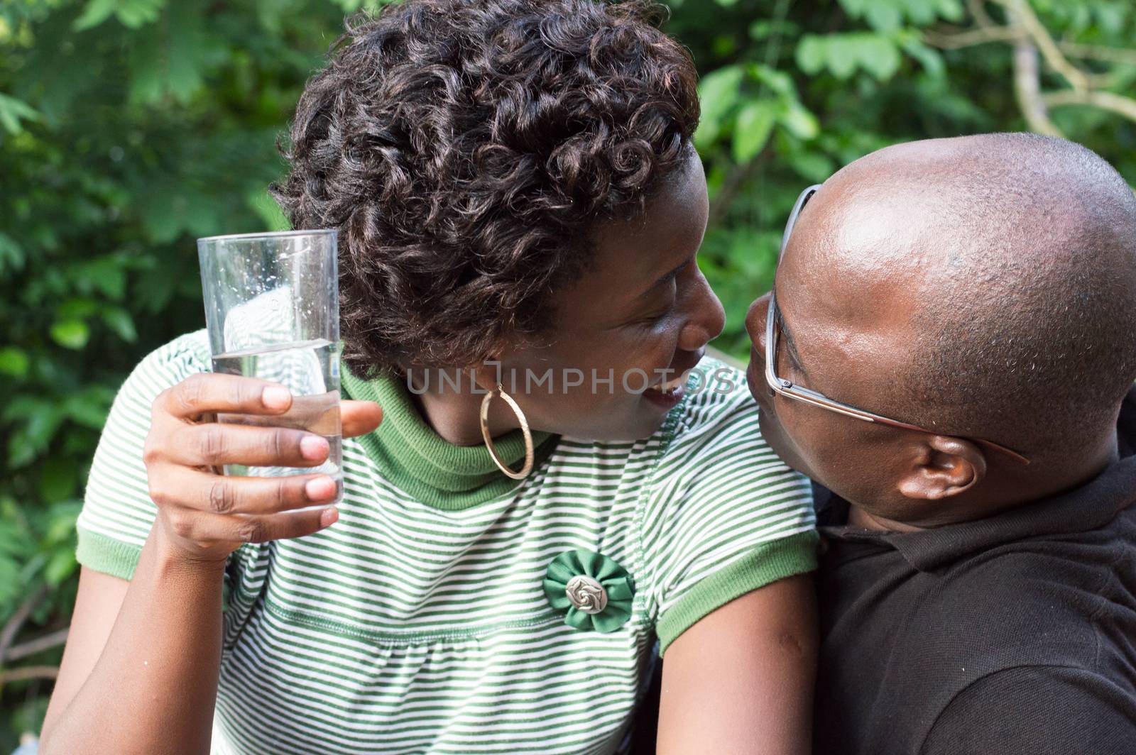 young woman kissing her boyfriend with a glass of water in hand.