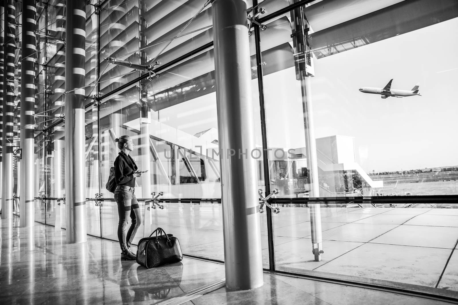 Young woman waiting at airport, looking through the gate window. by kasto