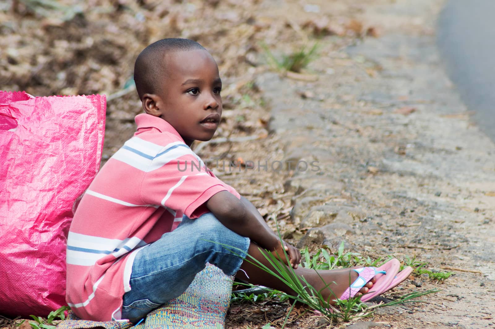 a child sitting on the ground and beside him a bag.