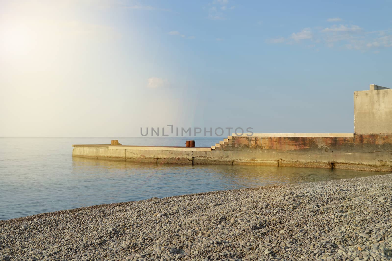 Sunrise on the sea with sun glare, pier on the shore in the early morning, calm, rest, summer holiday concept.