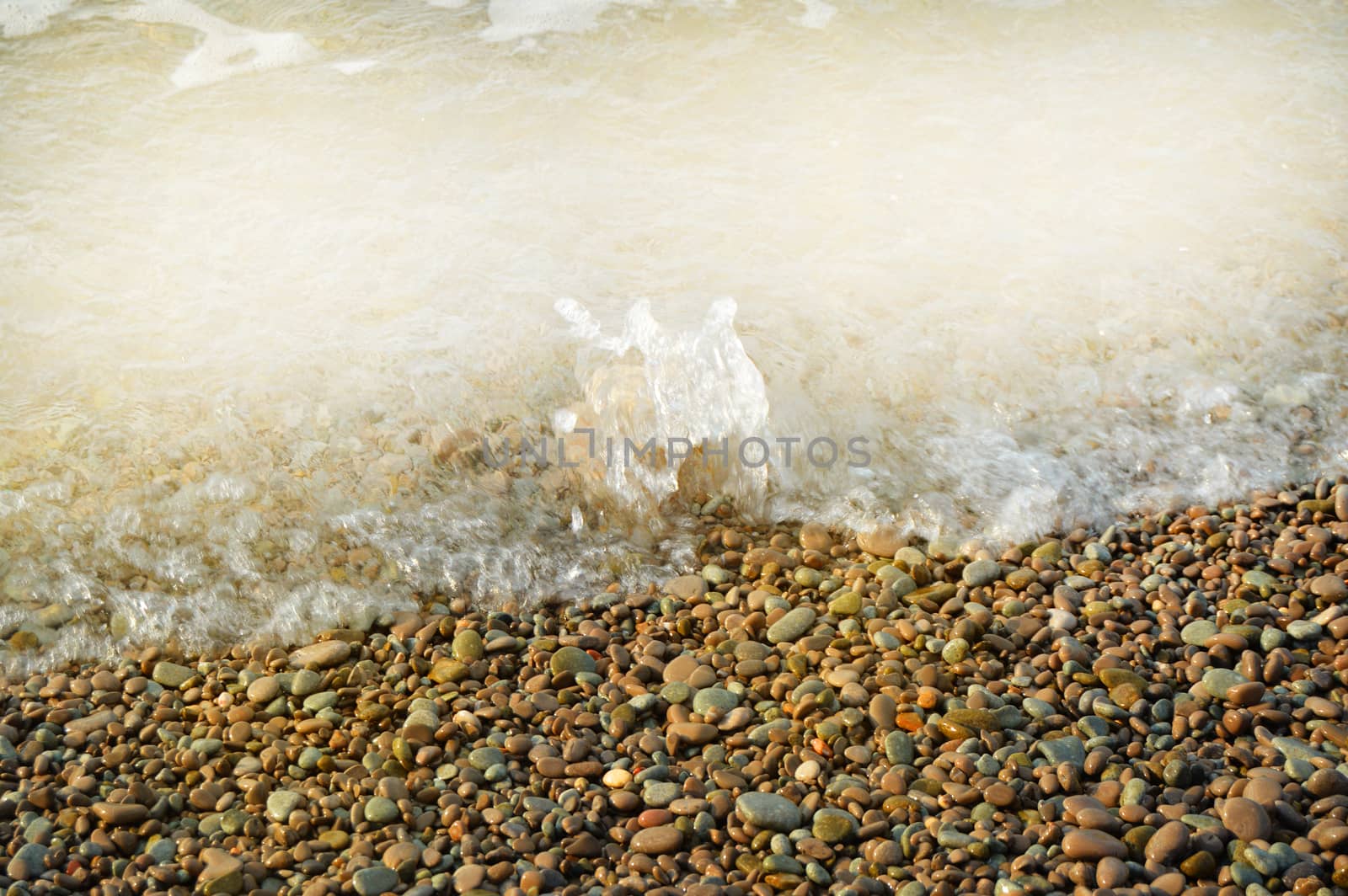 Sea wave on the shore of a pebble beach, water, foam, background.