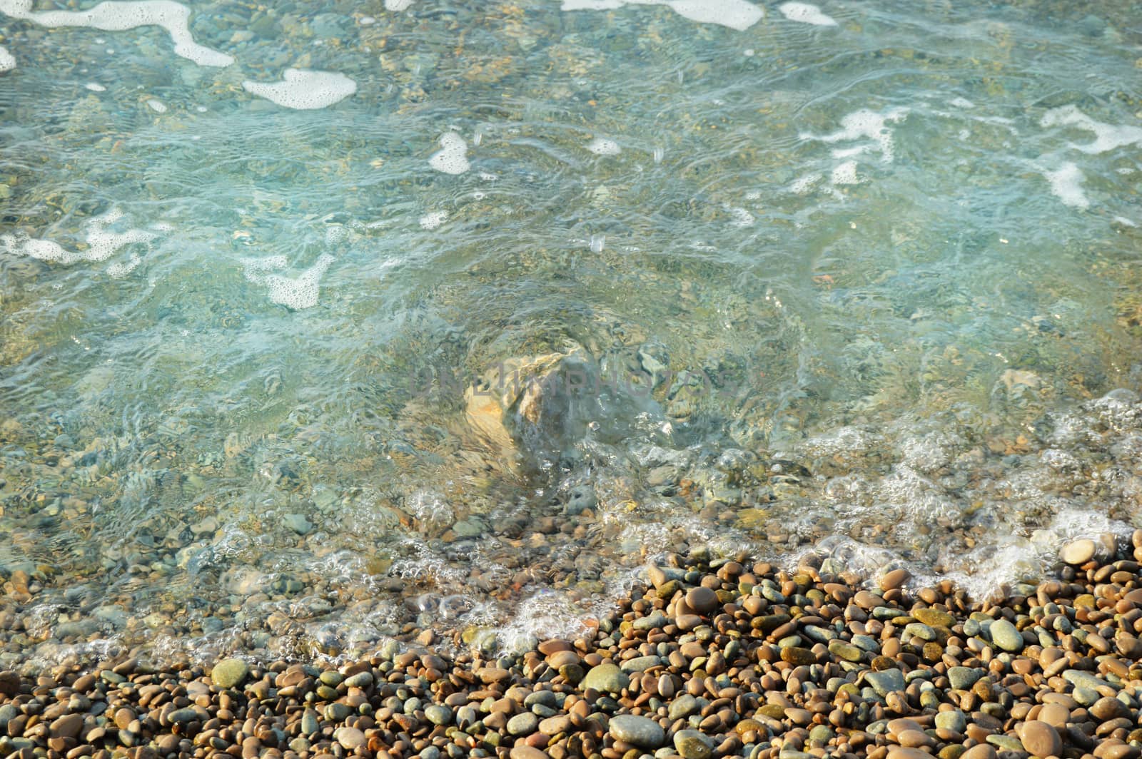 Sea wave on the shore of a pebble beach, water, foam, background.