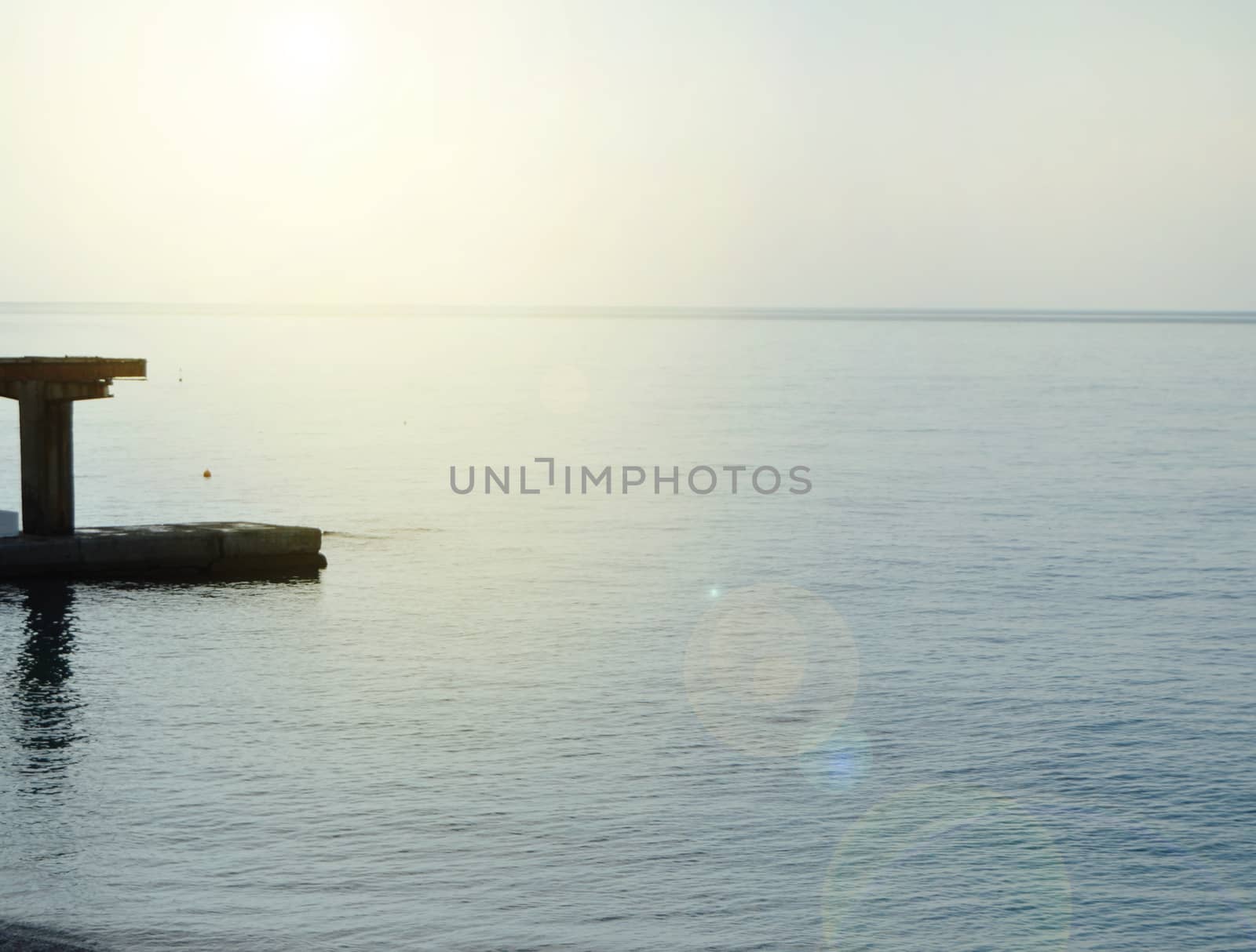 Sunrise on the sea with sun glare, pier on the shore in the early morning, calm, rest, summer holiday concept.