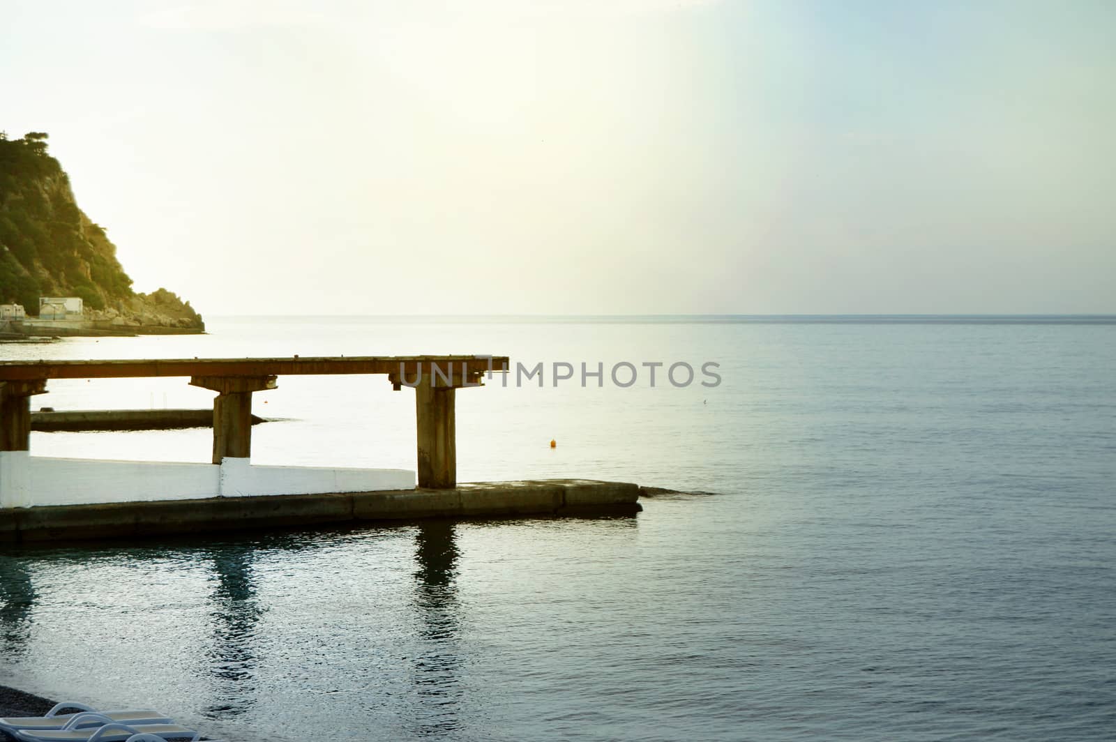 Sunrise on the sea with sun glare, pier on the shore in the early morning, calm, rest, summer holiday concept.