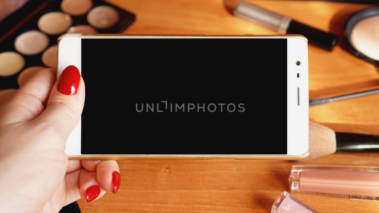 Smartphone with empty screen and cosmetics on wooden background. phone mockup by natali_brill