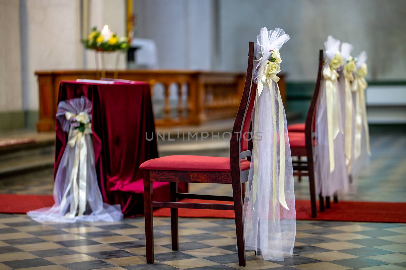 Beautiful floral wedding decoration in a church. Christian church decoration for wedding marriage ceremony. Wedding decor for chairs from flowers, veils and ribbons in church.
