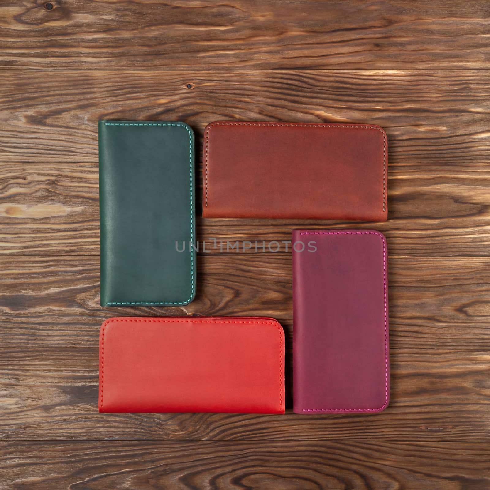 Four handmade leather porte-monnaie on wooden textured background. Up to down view. Stock photo of luxury accessories.