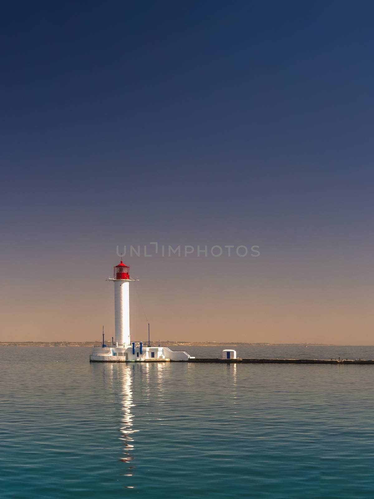 Lighthouse at the entrance to the harbor of the Odessa port, the sea gates of Ukraine in a sunny summer day