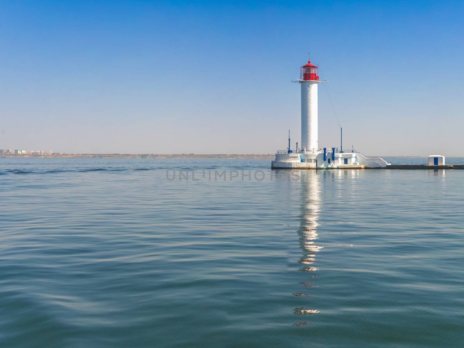 Lighthouse at the entrance to the harbor of the Odessa port, the sea gates of Ukraine in a sunny summer day