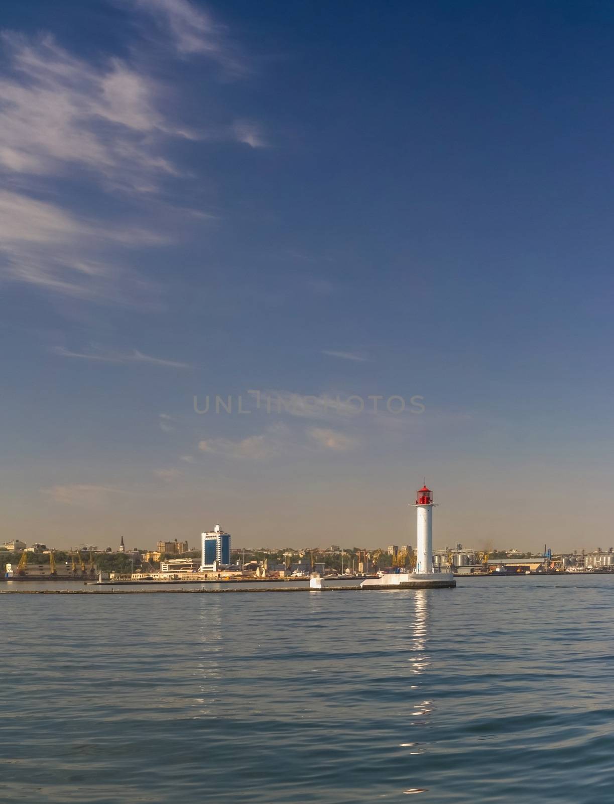 Lighthouse at the entrance to the harbor of the Odessa port, the sea gates of Ukraine in a sunny summer day