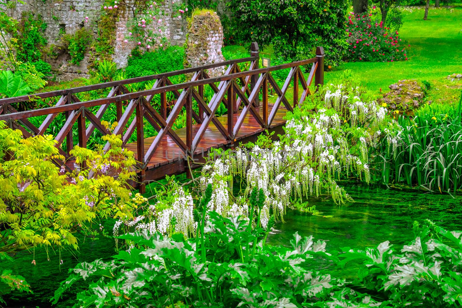 fairy tale bridge vivid green river wooden full of flowers in ornamental garden .