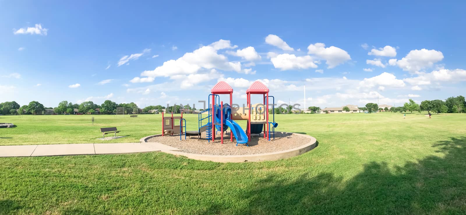 Panorama view colorful playground at public park in Texas, America with cloud blue sky on green grass lawn