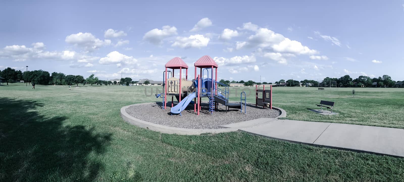 Panorama view colorful playground at public park in Texas, America with cloud blue sky on green grass lawn