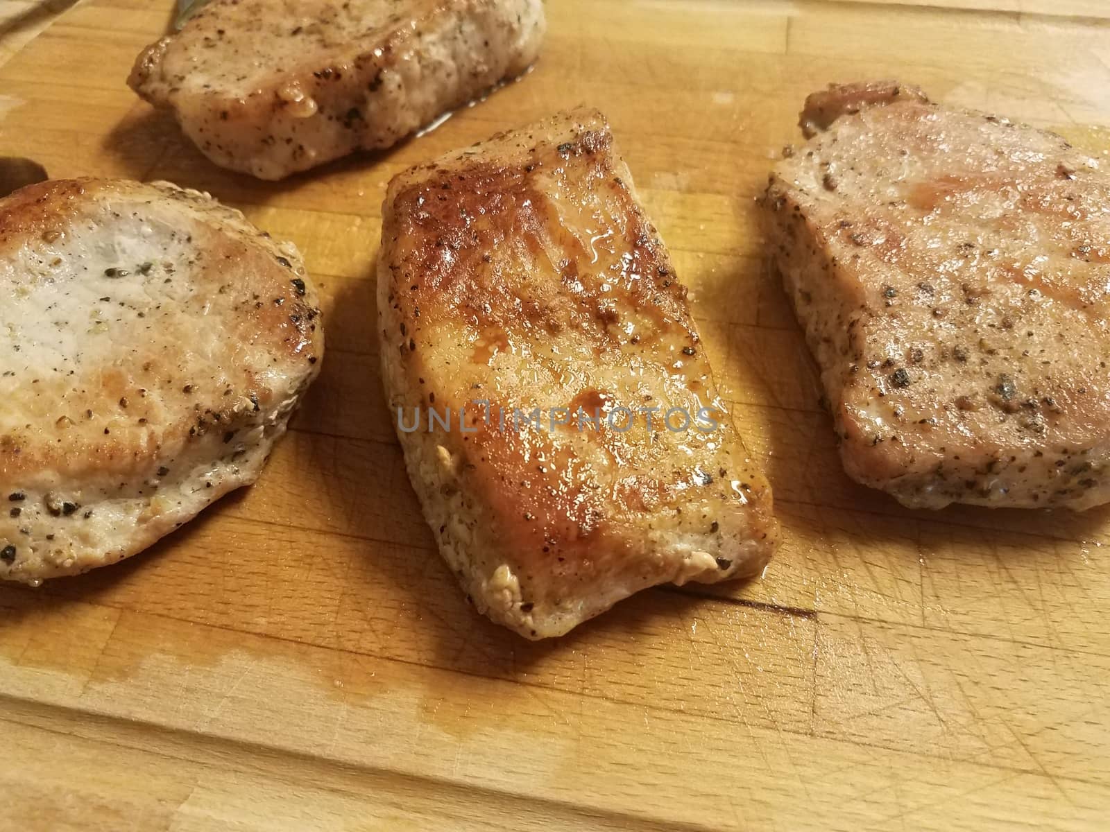 cooked pork chops with seasoning on wood cutting board and juices