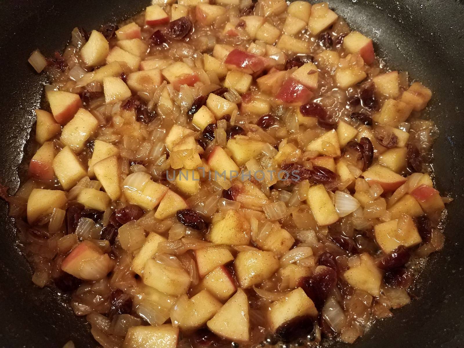 apples and cranberries and fruit in sauce cooking in a frying pan