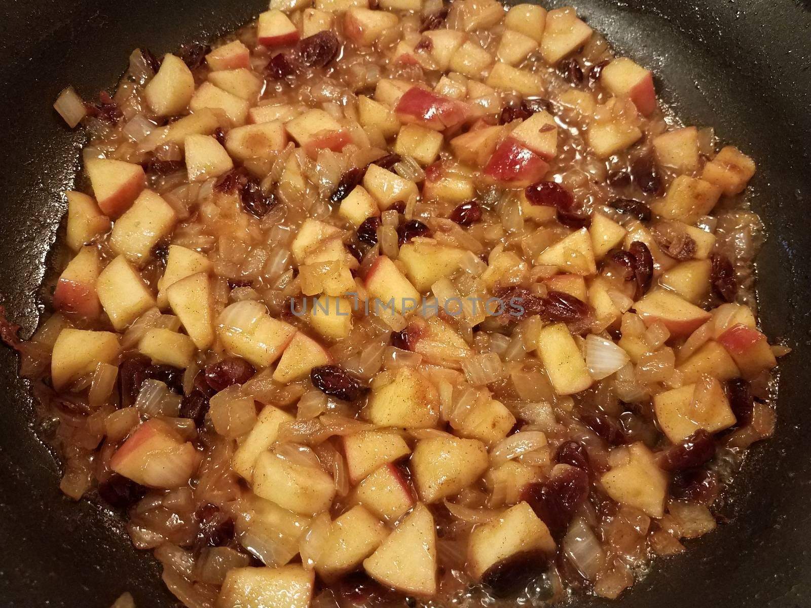 apples and cranberries and fruit in sauce cooking in a frying pan