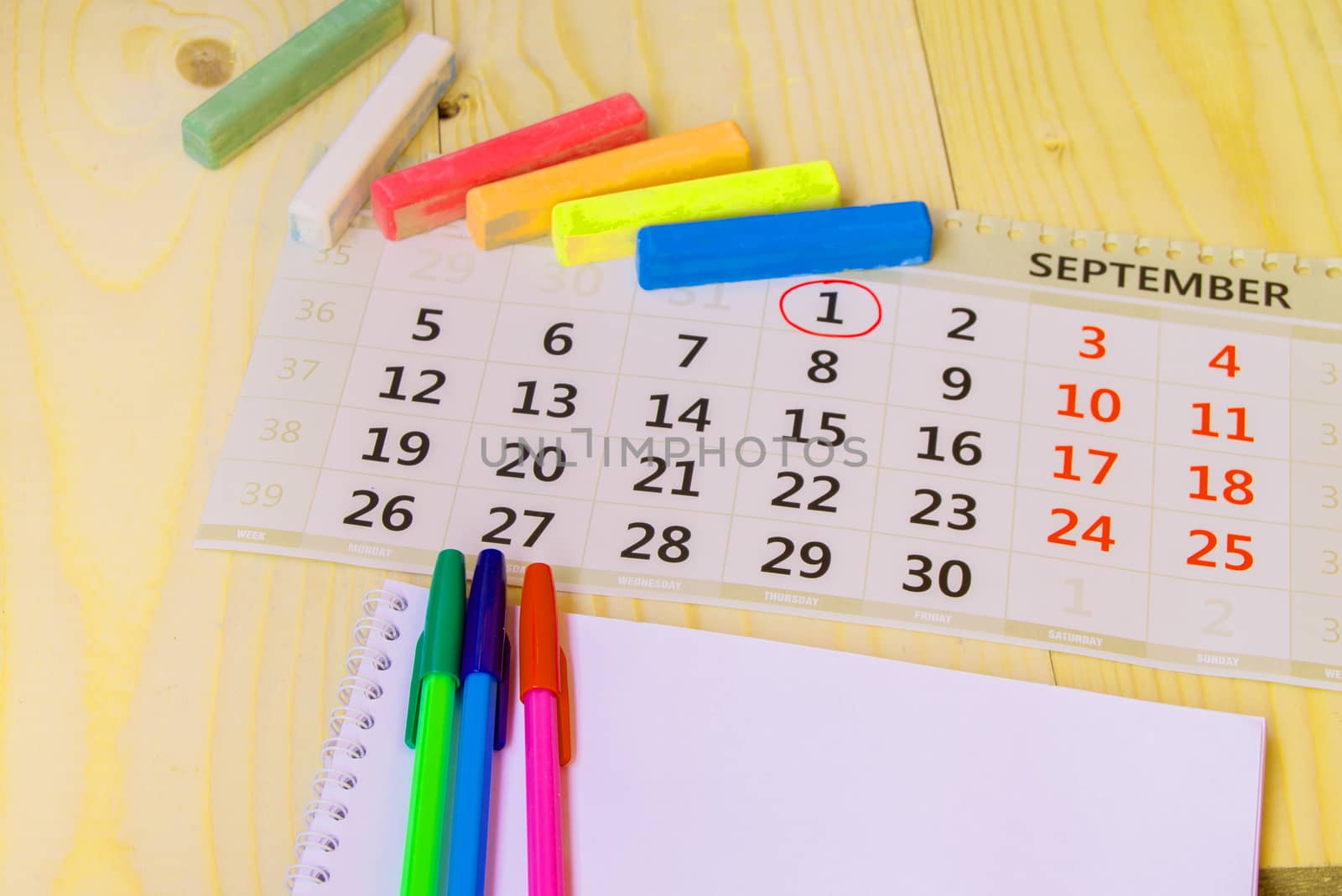 Back to school, calendar, colored chalk on wooden background.