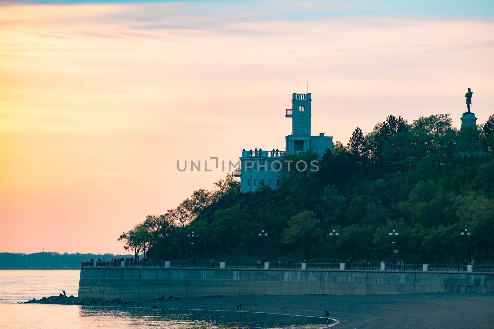 Sunset on the embankment of the Amur river in Khabarovsk. The sun set over the horizon. The embankment is lit by lanterns.