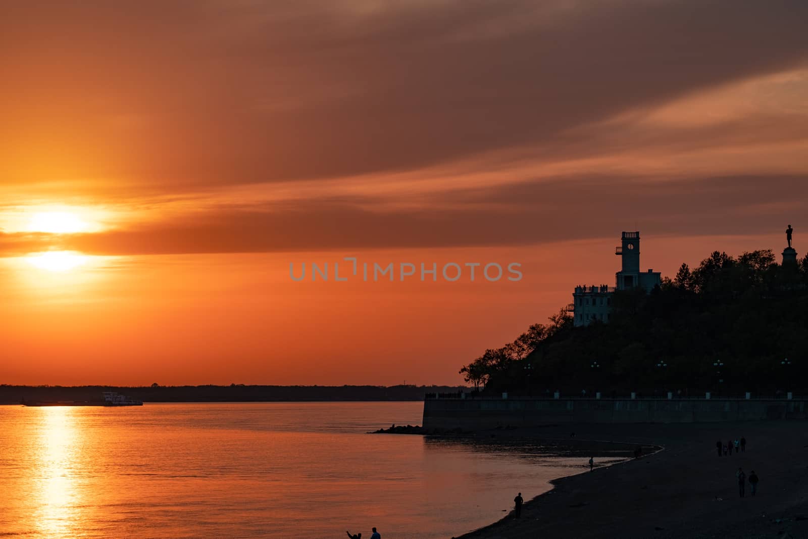 Sunset on the embankment of the Amur river in Khabarovsk. The sun set over the horizon. The embankment is lit by lanterns.